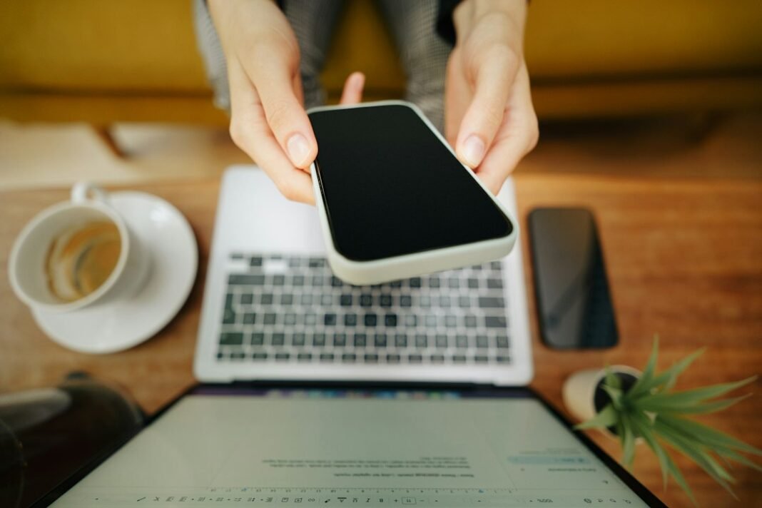 Pametni telefon i laptop na stolu, ilustracija digitalnog bankarstva (Unsplash, Jakub Żerdzicki)